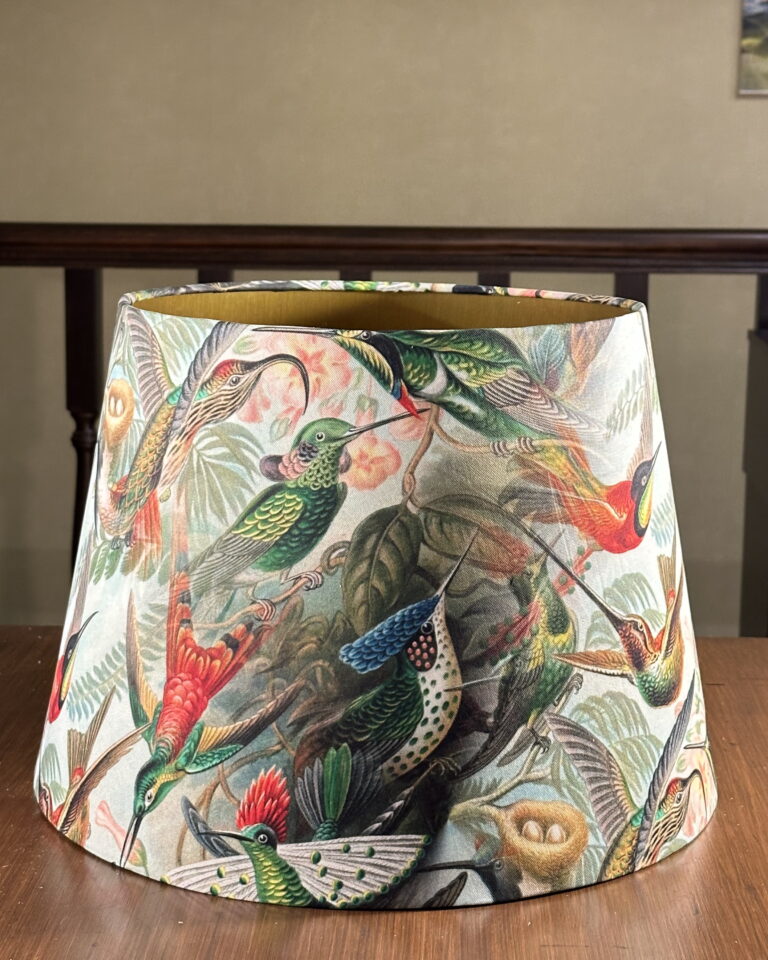 Front view of the hummingbird empire lampshade with brushed gold interior and vibrant tropical pattern.