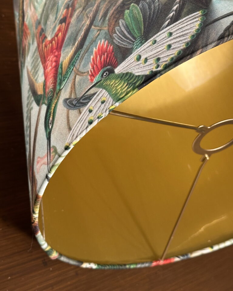 Side view of the hummingbird empire lampshade with brushed gold interior and vibrant tropical pattern.