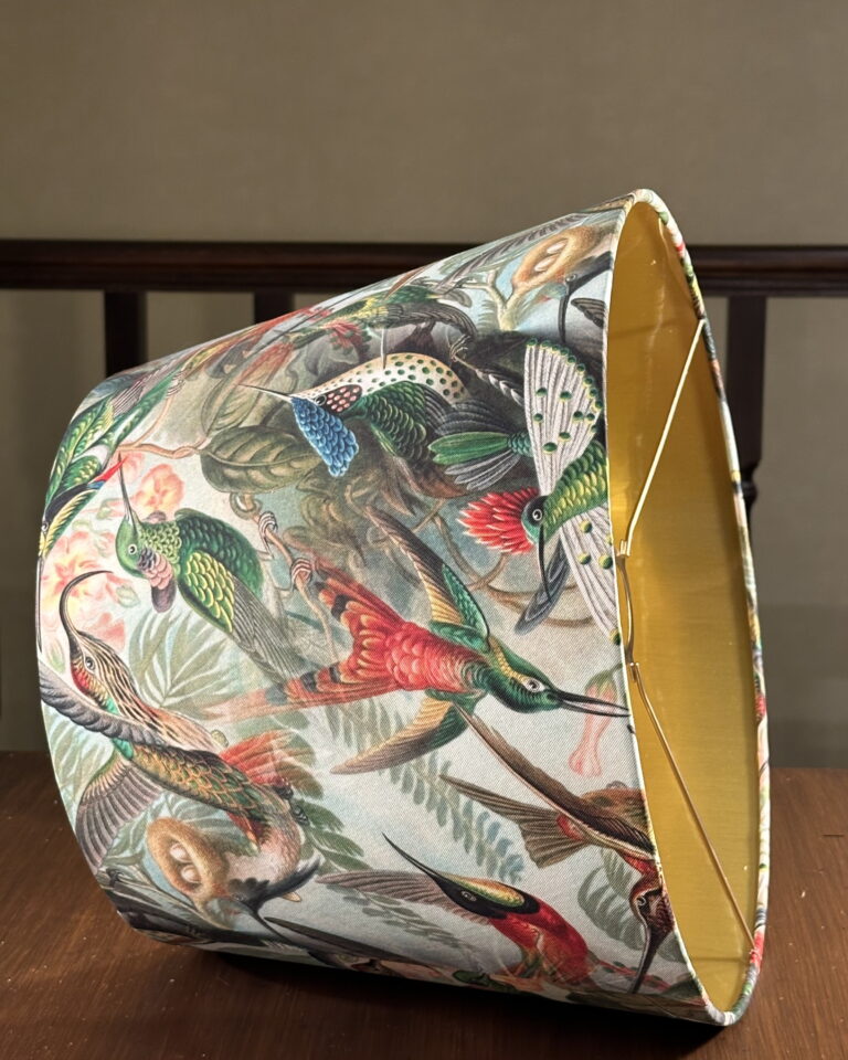 Detailed photo of the handmade hummingbird empire lampshade, brushed gold interior and artistic tropical print.
