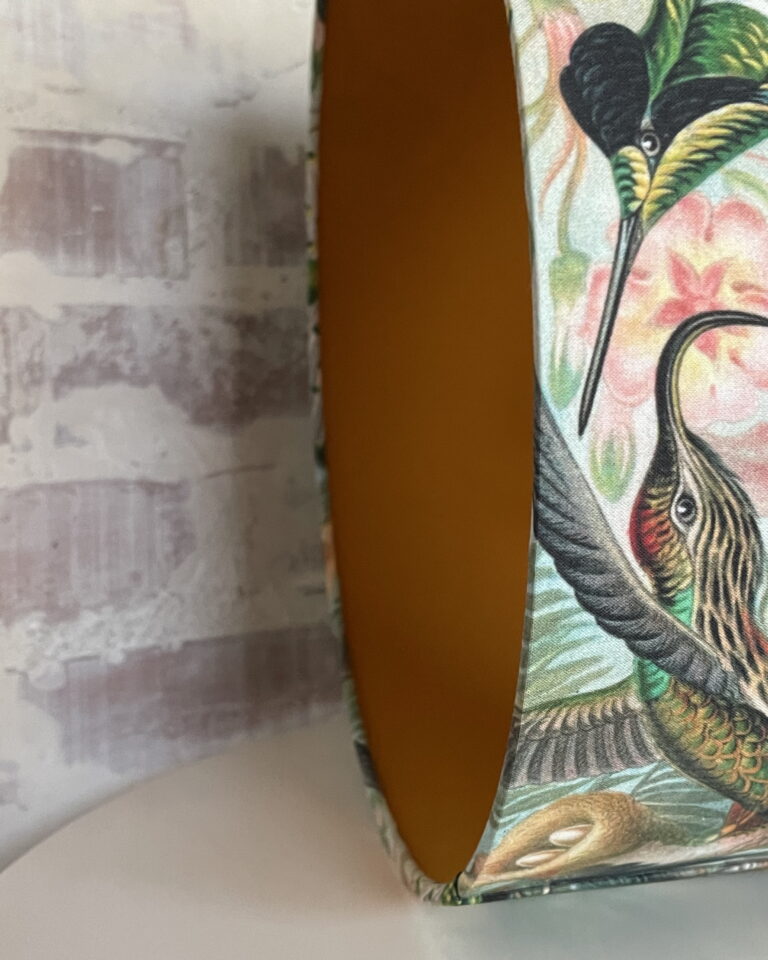 Handmade double-sided lampshade with tropical hummingbird print and warm amber interior fabric — detail of rim and lining.