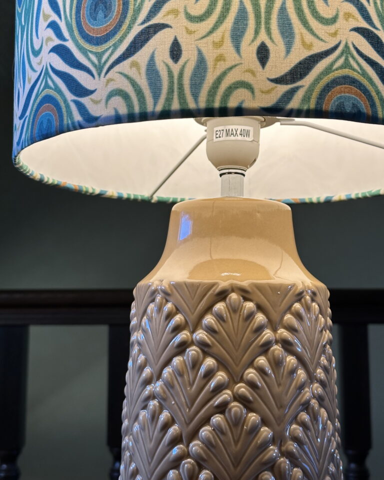 Detail of Peacock pattern fabric in teal, blue, and gold tones on handmade Art Deco lampshade.