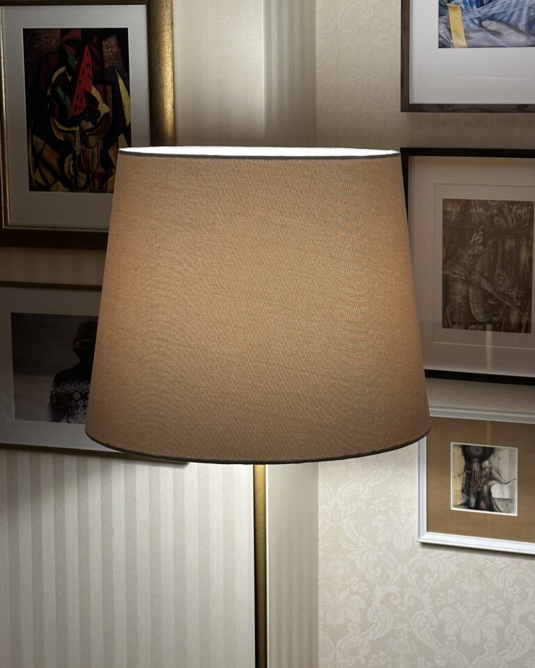 Beige textured linen lampshade glowing softly on a lamp base